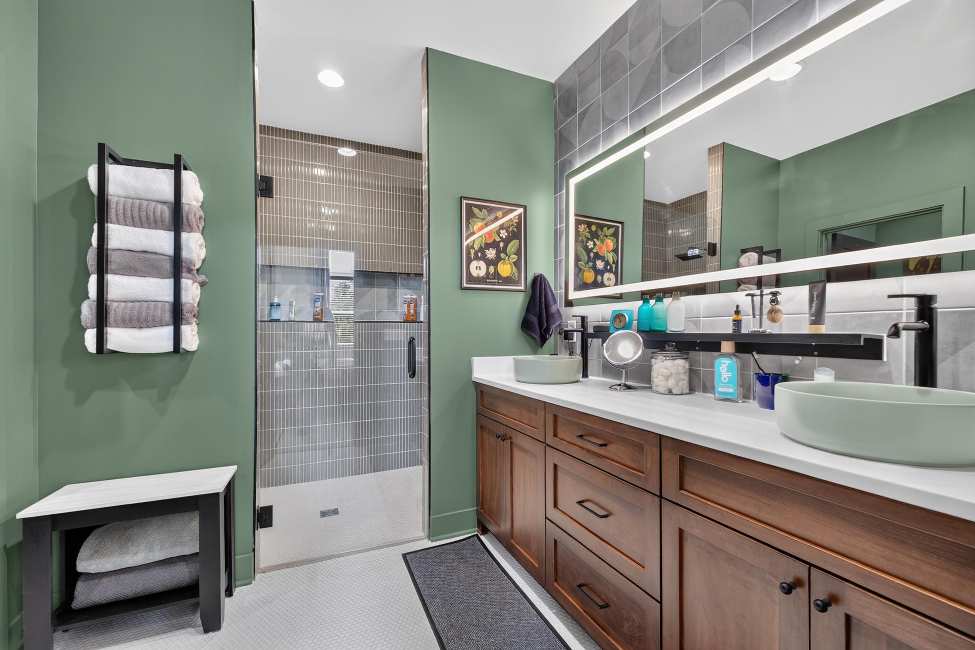 Primary bathroom with sage green walls and crisp lines around tile and vanity