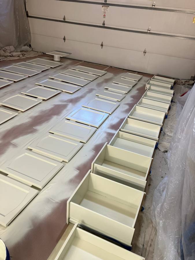 Freshly painted white cabinet doors and drawers drying in rows
